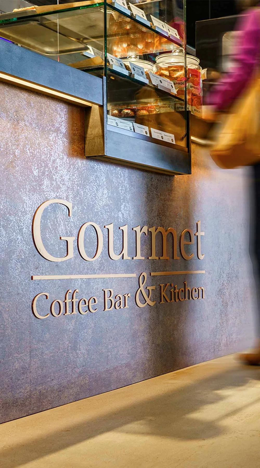 The Gourmet Coffee Bar & Kitchen name on a copper-toned wall